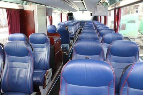 Просторий салон автобуса ТрансТемпо з комфортабельними синіми шкіряними кріслами, мультимедійними моніторами під стелею та панорамним склінням — якісний сервіс на рейсах atatickets.com.