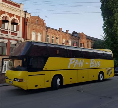 Автобус перевізника ПАН-БУС на міській вулиці, міжміський туристичний автобус з фірмовим написом, що обслуговує регулярні пасажирські рейси.