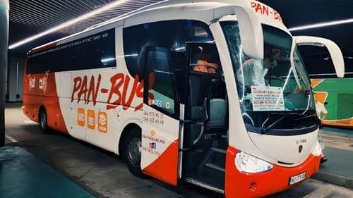 Автобус перевізника PAN-BUS на автостанції в нічний час, сучасний міжміський автобус із фірмовим брендуванням, готовий до виконання міжнародного рейсу.